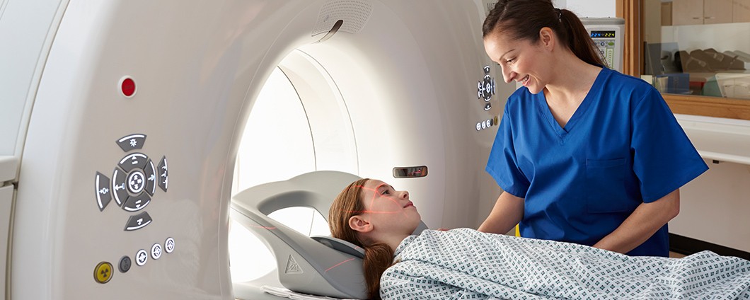 Child patient being comforted by imaging technician during a brain scan