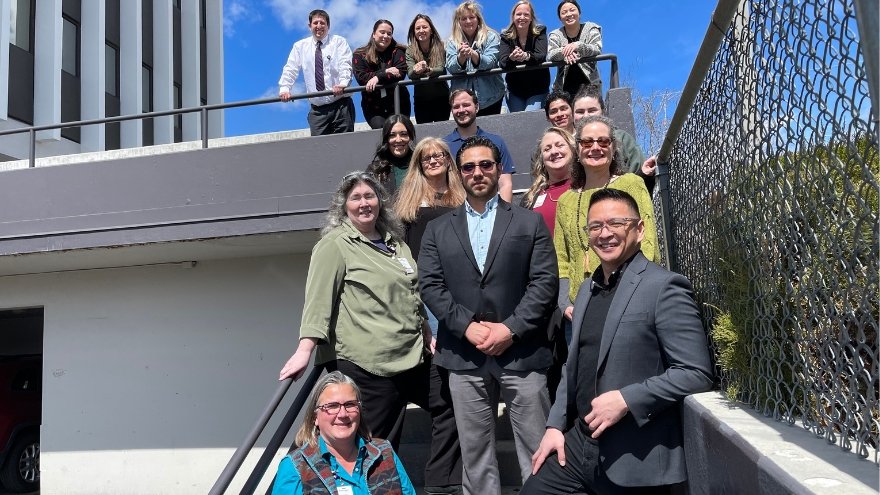 A group of finance staff members at Renown Health pose outside on a staircase for a group photo.