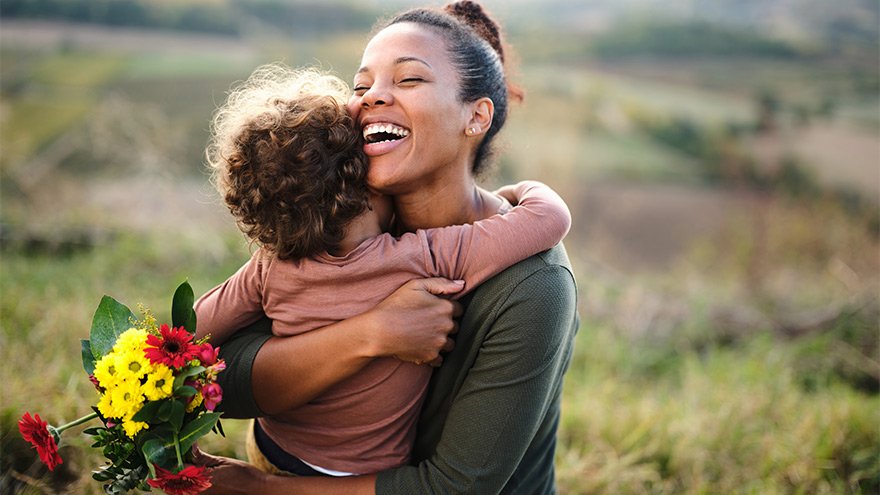 Happy woman embraces her young son in a field