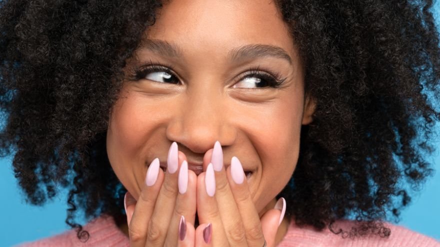 Woman smiling with hands over mouth