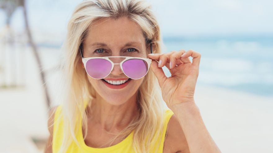 Woman at beach looking over her sunglasses
