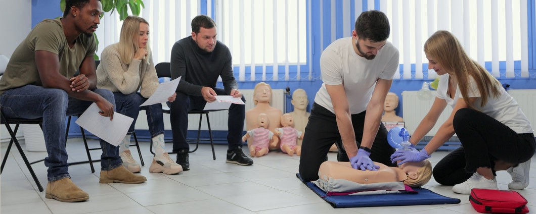 Male instructor teaching first Aid CPR technique to students