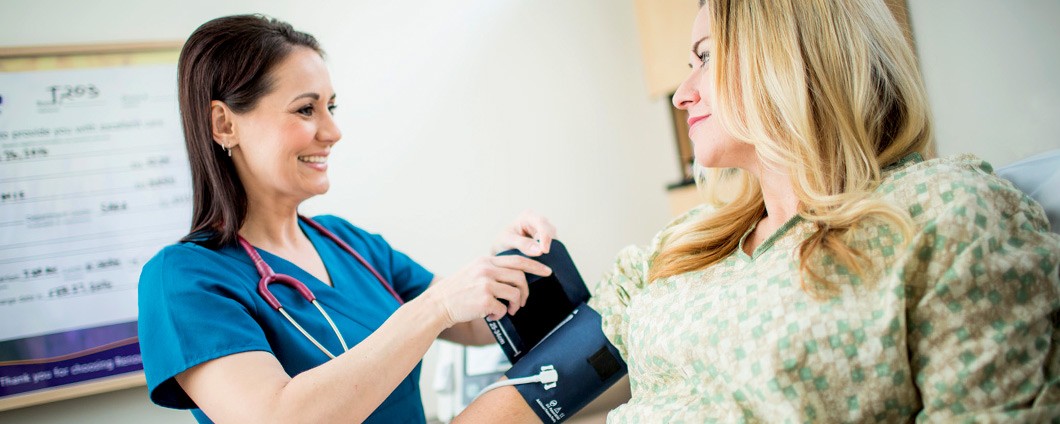 CNA taking patient's blood pressure