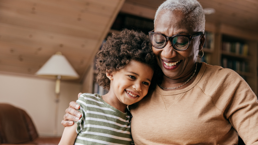 A grandma gives a side-hug to her grandchild as they both smile.