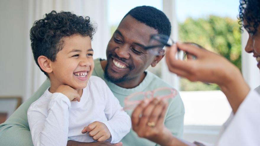 A child and his father work with a doctor to look at glasses options