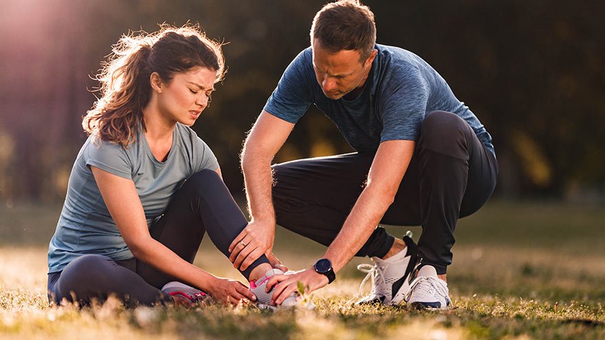 Man helping woman with sprained ankle