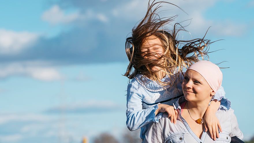 A woman with cancer plays with her daughter outside