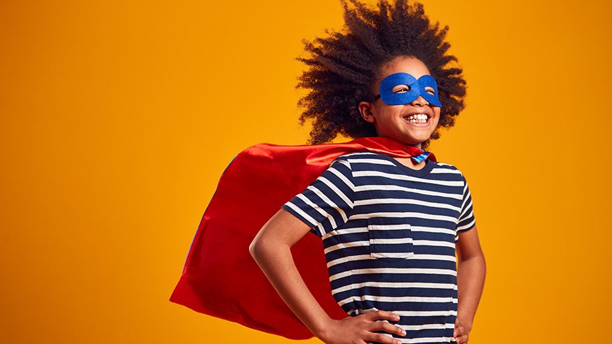 Studio Portrait Of Boy Dressed As Comic Book Superhero Against Yellow Background