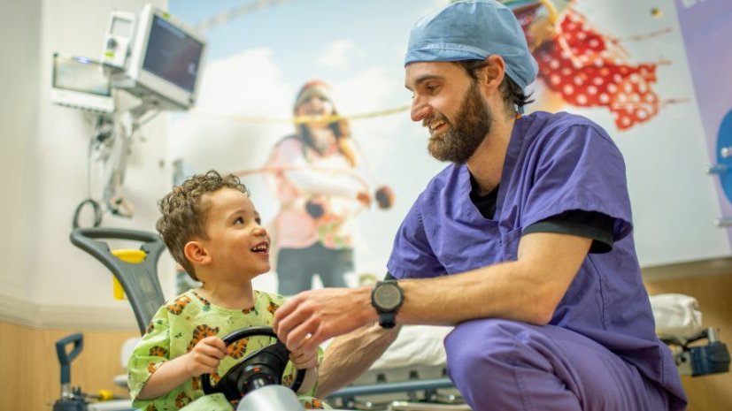 Renown Pediatric nurse smiles at children's hospital patient on toy car