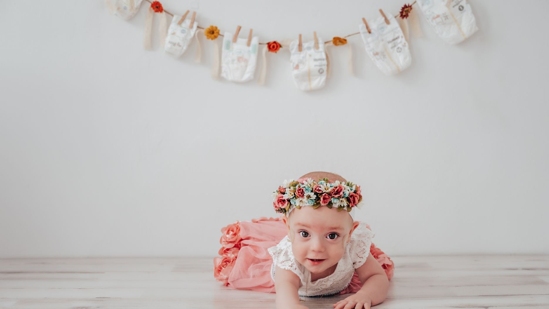 a small baby crawls toward the camera dressed in pink