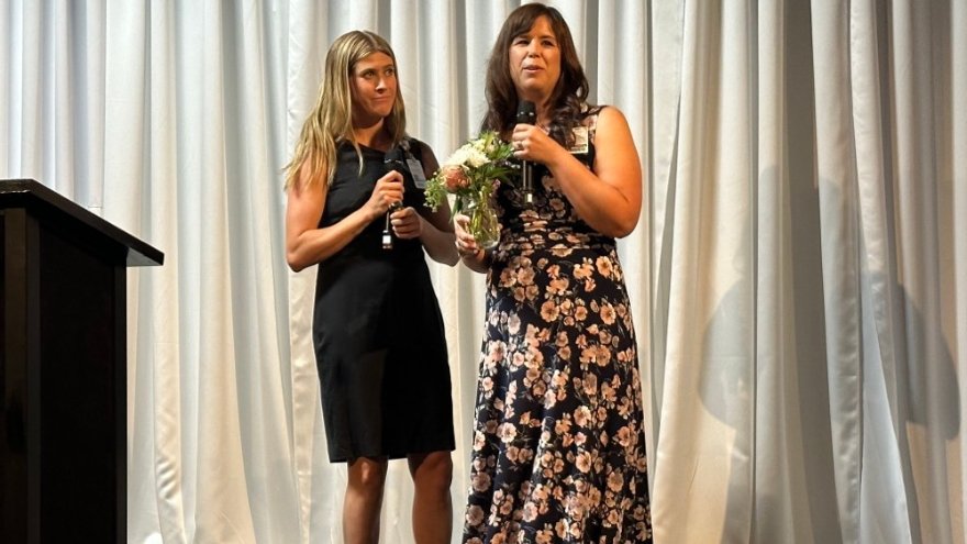 Wendy Peukert accepts an award onstage next to Shelbi Whitehead.