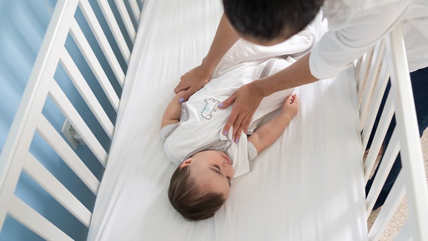 Parent helping baby practice safe sleep in crib