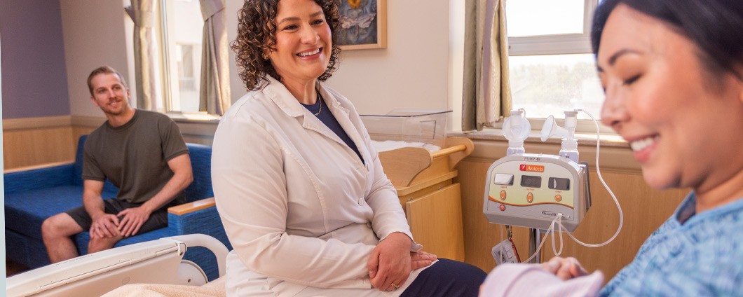 Renown Health lactation nurse consults with new mom and baby at the bedside