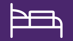 a white icon of a hospital bed on a purple background .