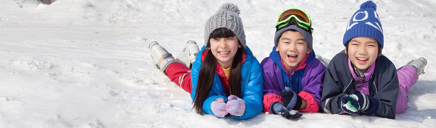 Three happy, smiling kids laying in snow