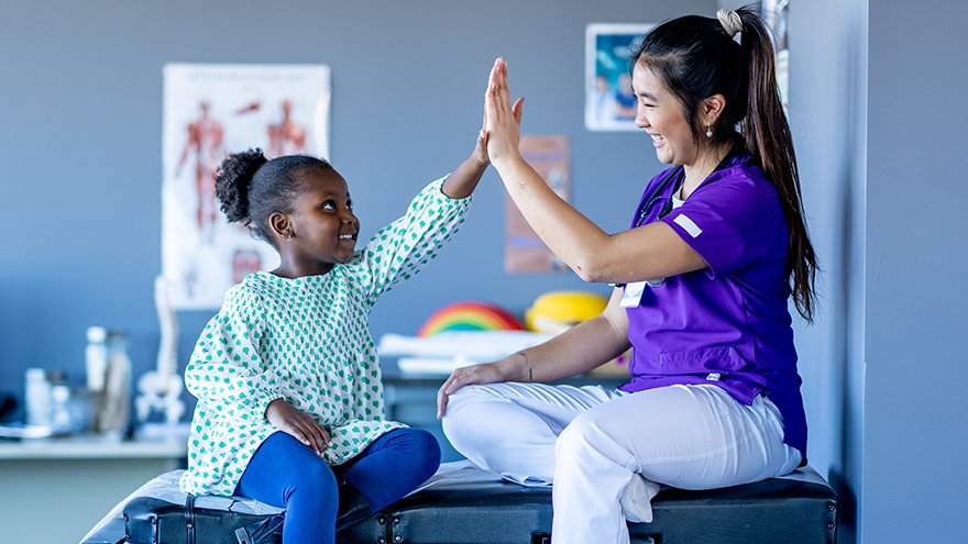 Nurse and child high-fiving in medical room