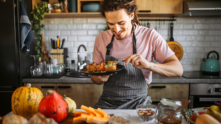 Young man eating delicious and healthy dessert, pumpkin with honey and cinnamon