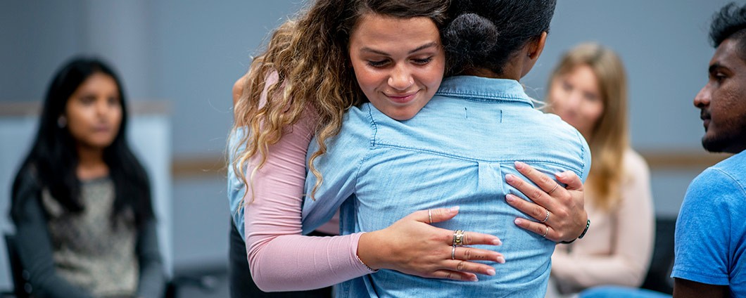 Teens embracing during group therapy session