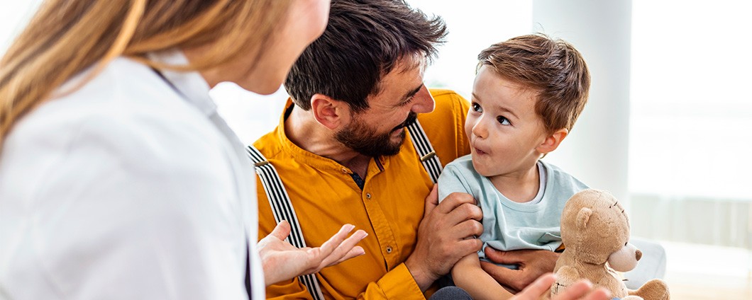 Young single father with little son holding teddy bear visiting child psychologist