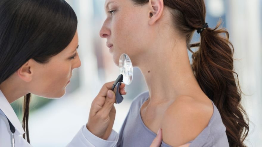 A dermatologist examines a female patients neck for sun spots or skin cancer