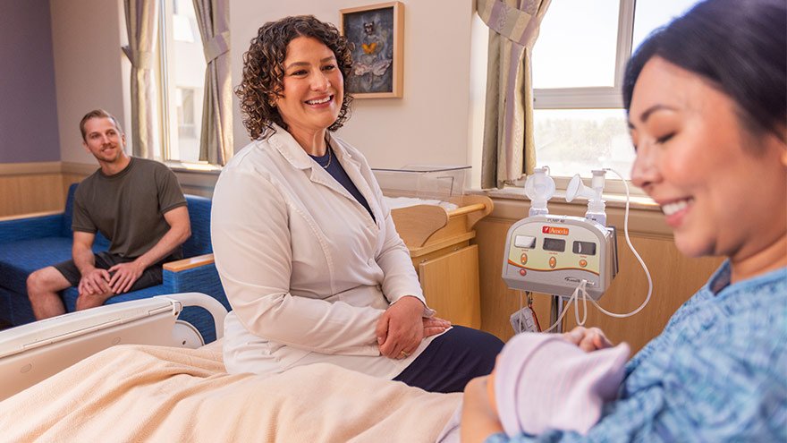 Renown Health lactation nurse consults with new mom and baby at the bedside