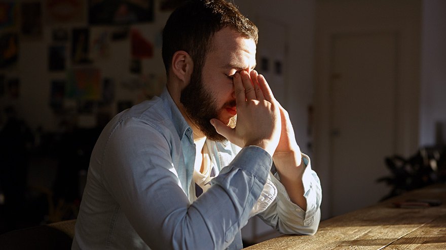 Unhappy man sitting at table with hands on his head