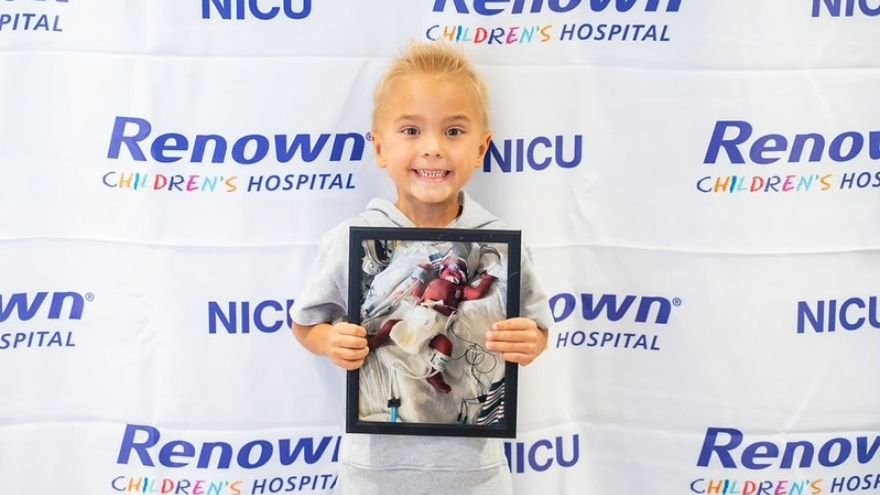 NICU Toddler posing with picture from time in NICU