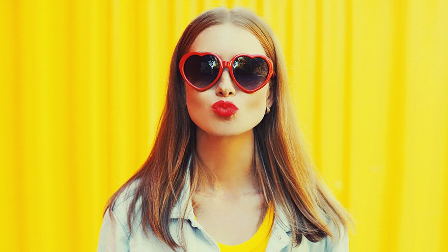 Woman wearing red heart glasses blowing kiss