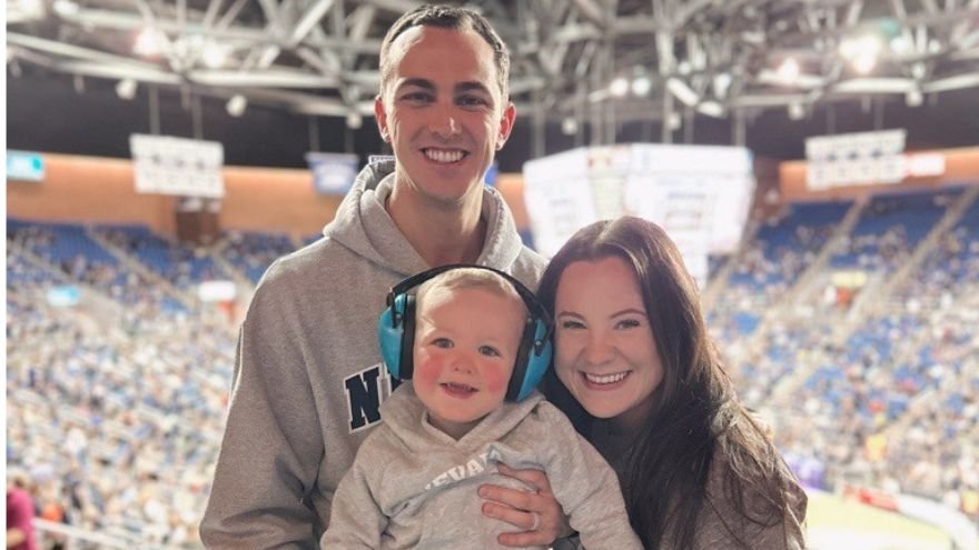Alex poses with wife and child at UNR basketball game
