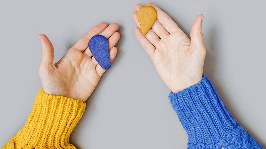 Hands holding two pieces of a broken heart