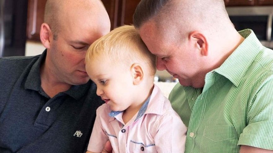 Chris and Jeffery cuddle their adopted son.