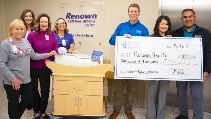 Team members from Renown Children's Hospital and Greater Nevada Credit Union pose for a photo featuring a $100,000 gift that will fund 22 bassinets, much like the one showed here.