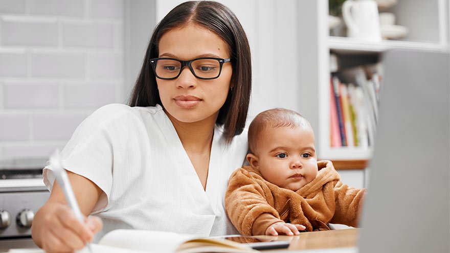 Shot of a young mother writing in a notebook while holding her son at home