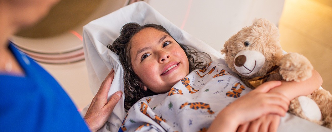 Young patient holding teddy bear receiving care at Renown Health