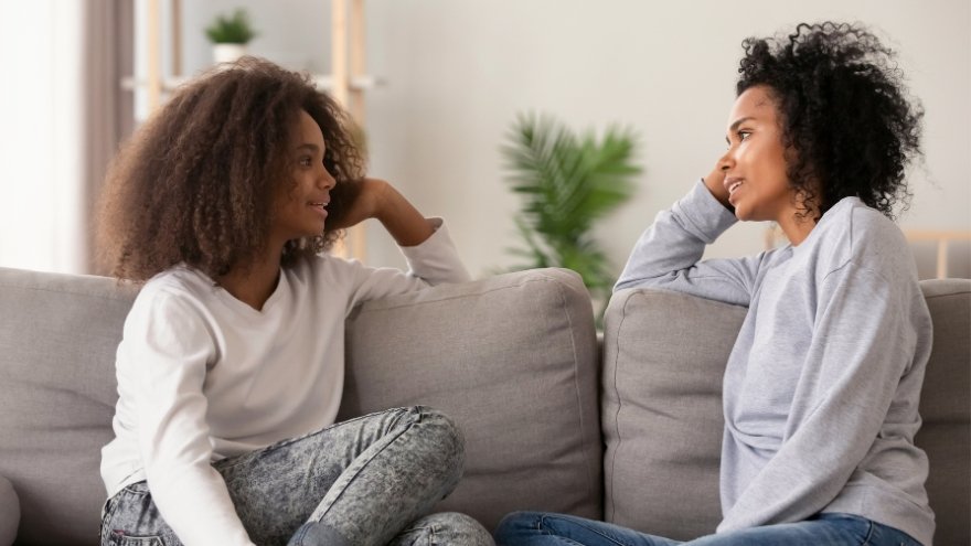 Mom and daughter sitting on couch having a conversation