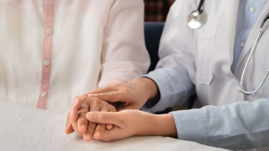 A doctor consults a patient and offers support by holding hand