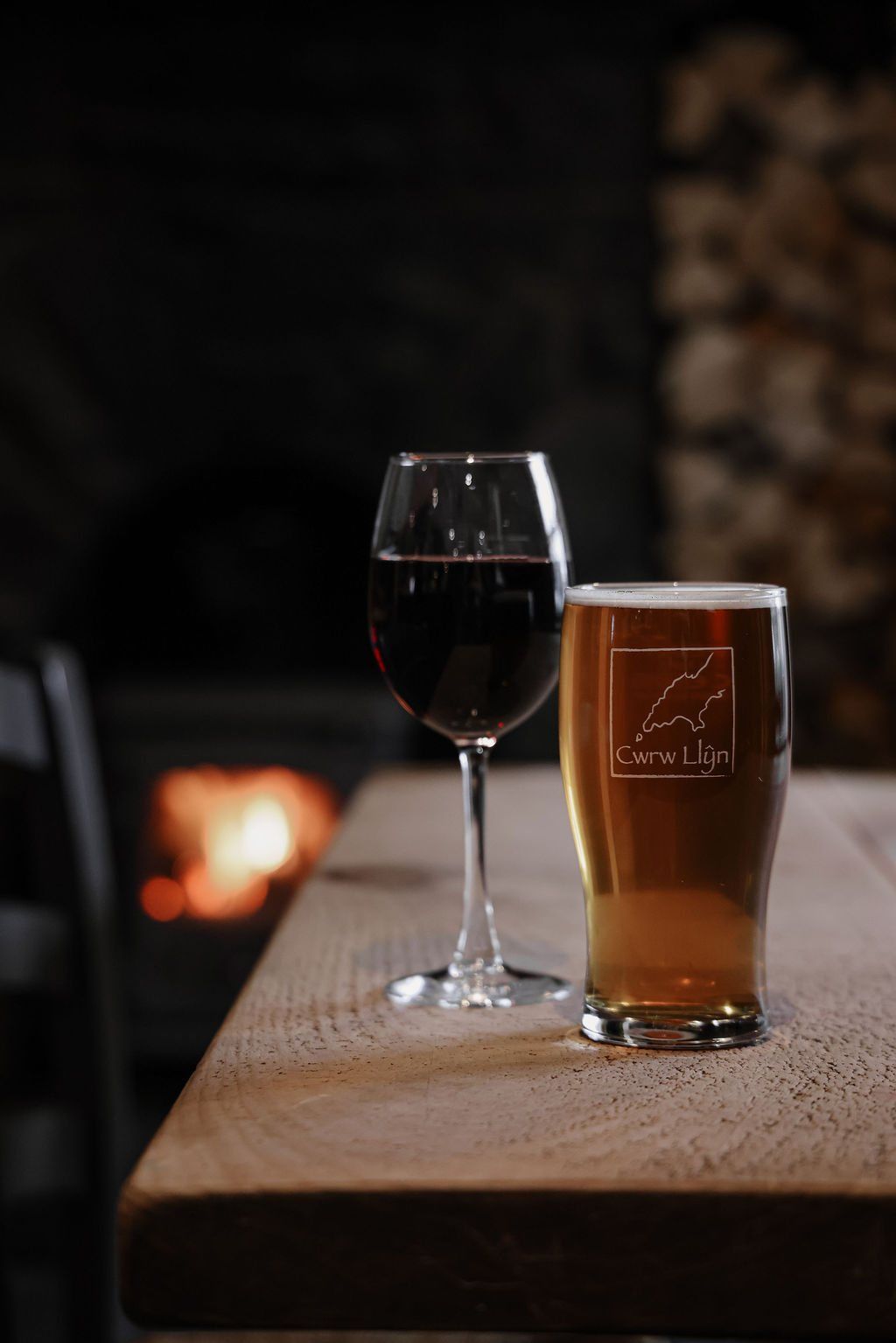 A pint and a glass of red wine on a table by the fire