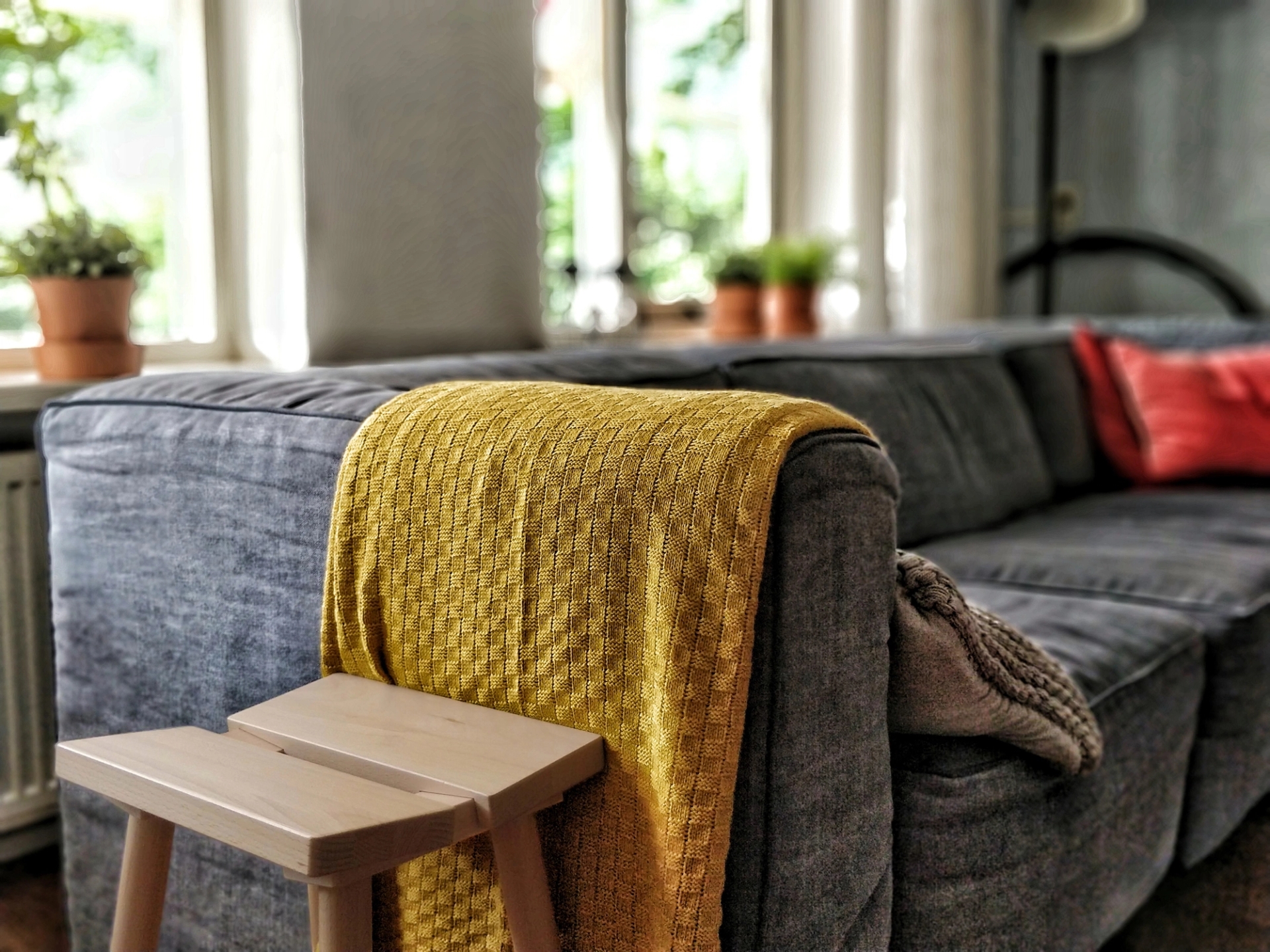 Yellow throw draped over a grey sofa in a living room.