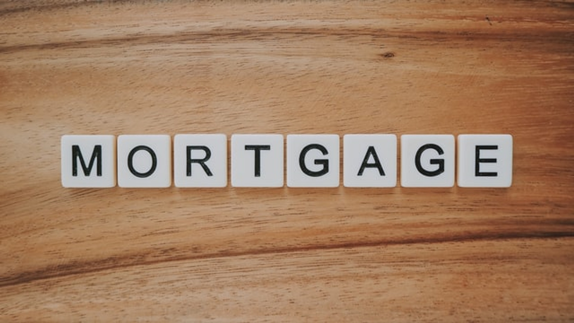 Scrabble tiles spelling out "mortgage" on a wooden table