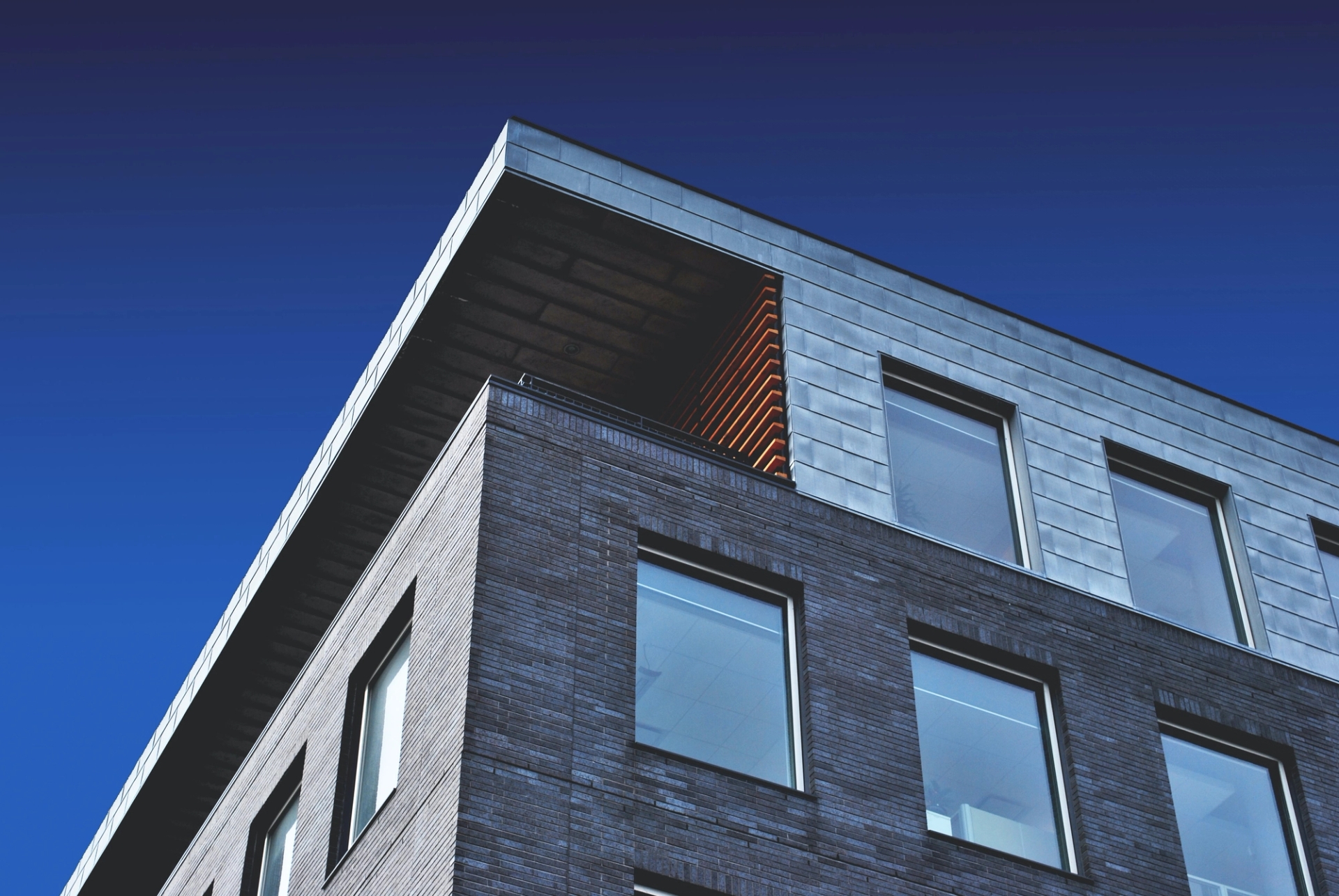 Looking up at the corner of a block of flats with the blue sky above