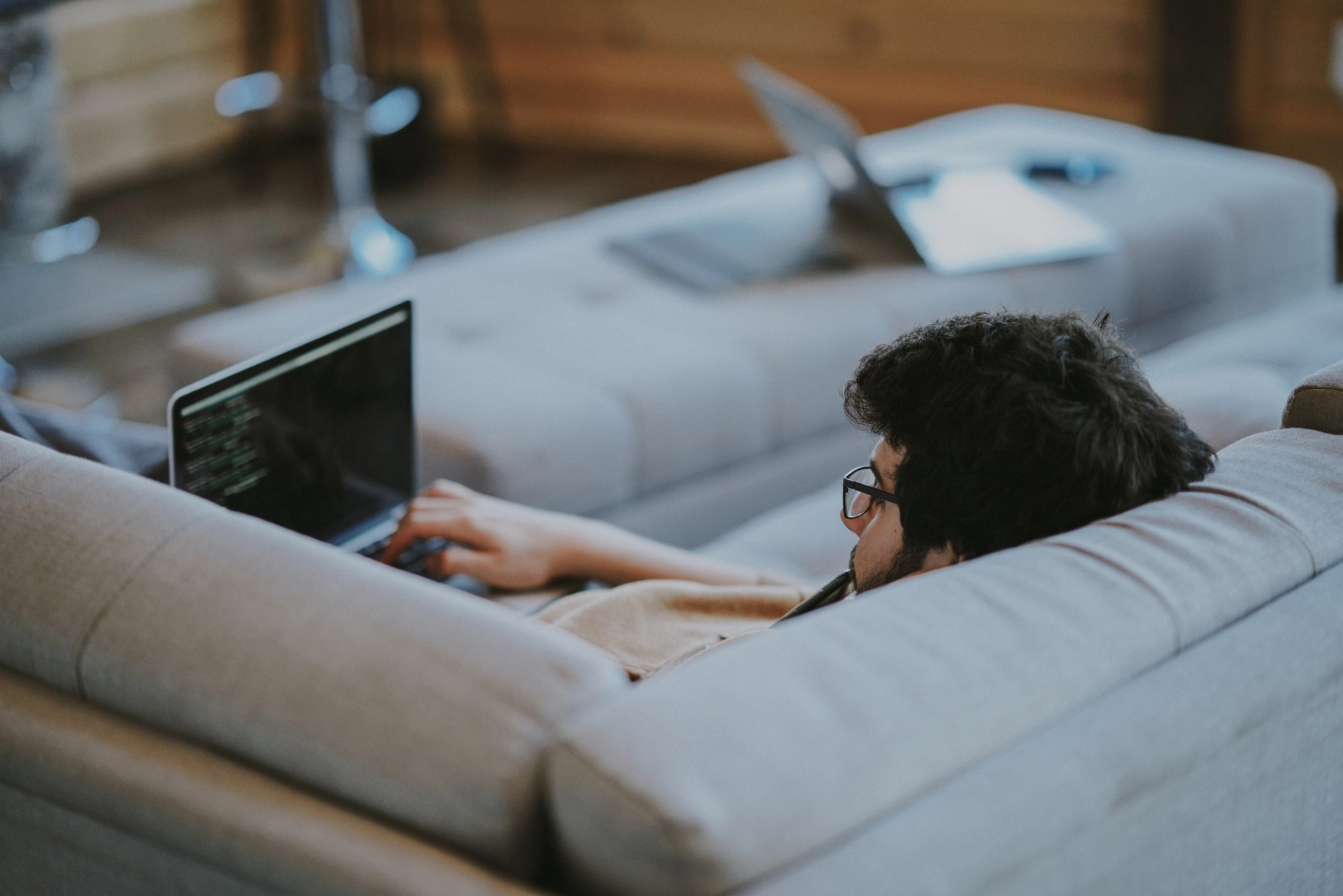 A man sat on his sofa with his laptop research a viewing