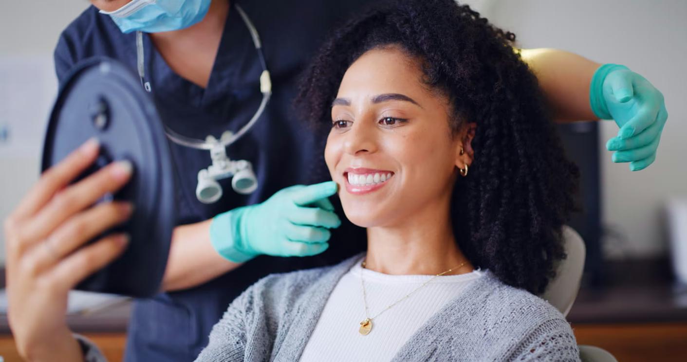 Patient admiring her new dental crown in a hand mirror at Bell Dental