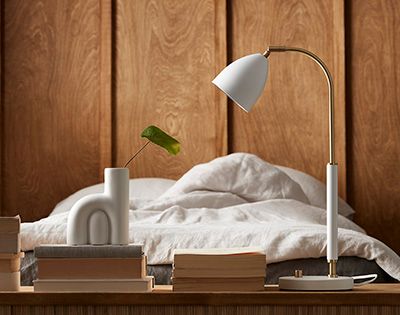Vit bordslampa framför en säng