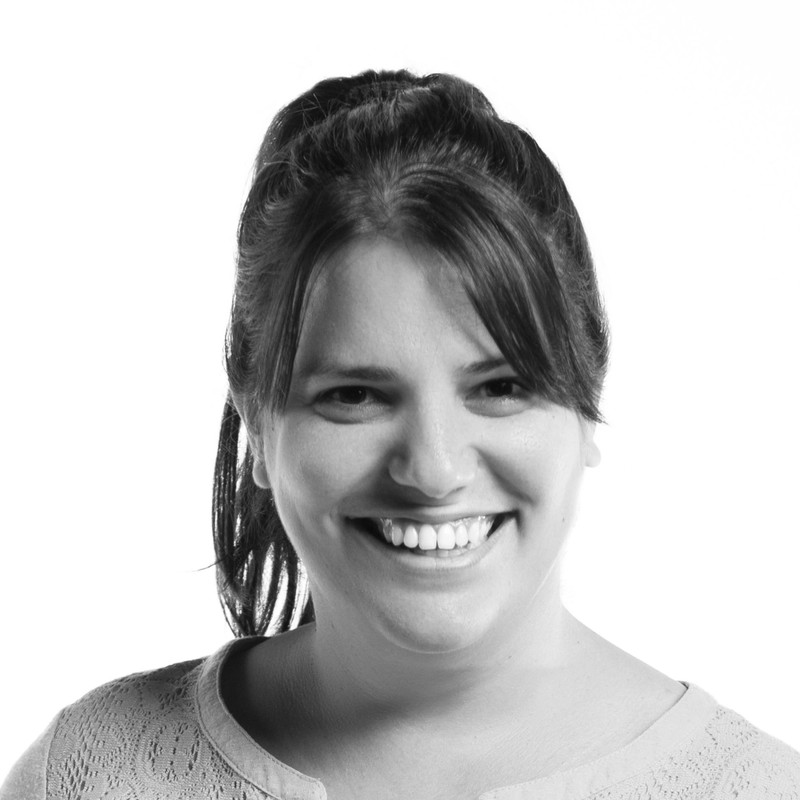 Headshot of Elaine Díaz Rodríguez with brown hair and smiling, in front of a grey background.