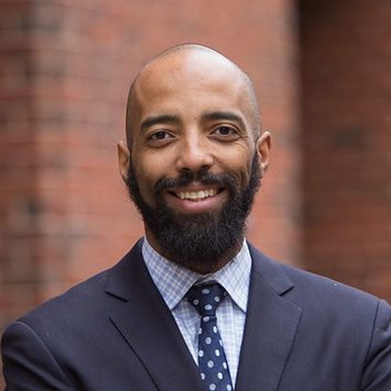 Headshot of Vincent Southerland with bald head, a beard, in front of a brown brick background