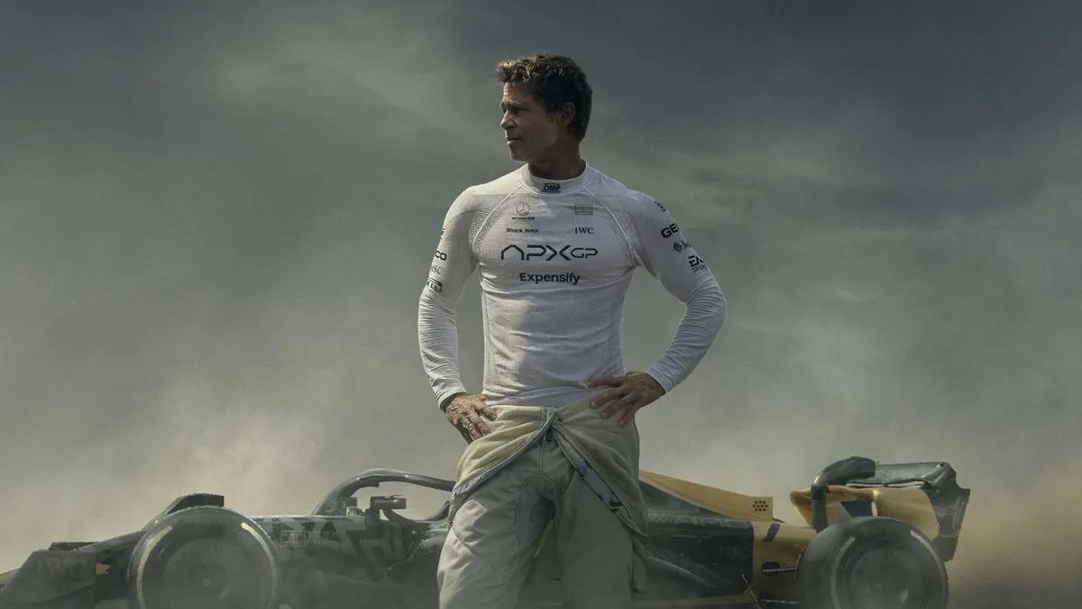 a cinematic shot of Brad Pitt in white racing gear standing next to his formula one car, moody sky, dust and smoke