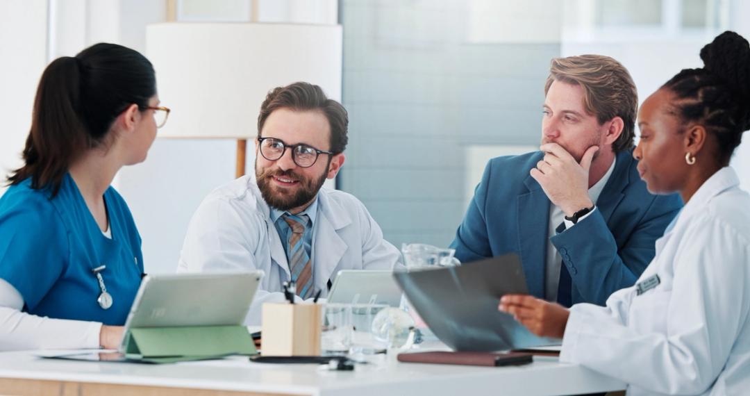 Consultants and doctors meeting around a table in a hospital