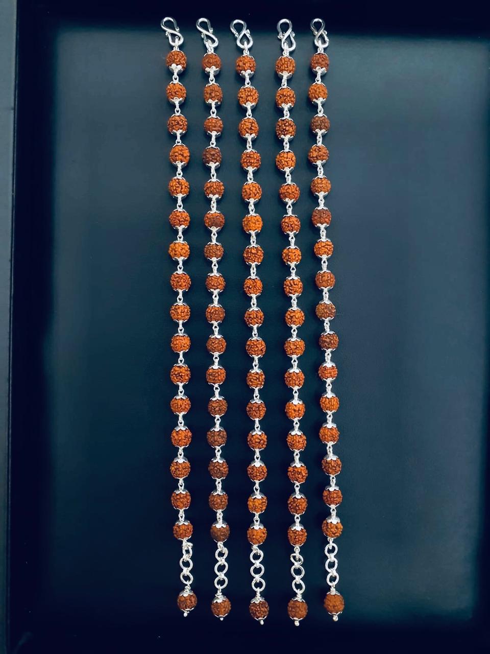 Five identical chains of textured Rudraksha beads with silver-toned floral caps, S-hook clasps, and terminal capped beads on a dark background