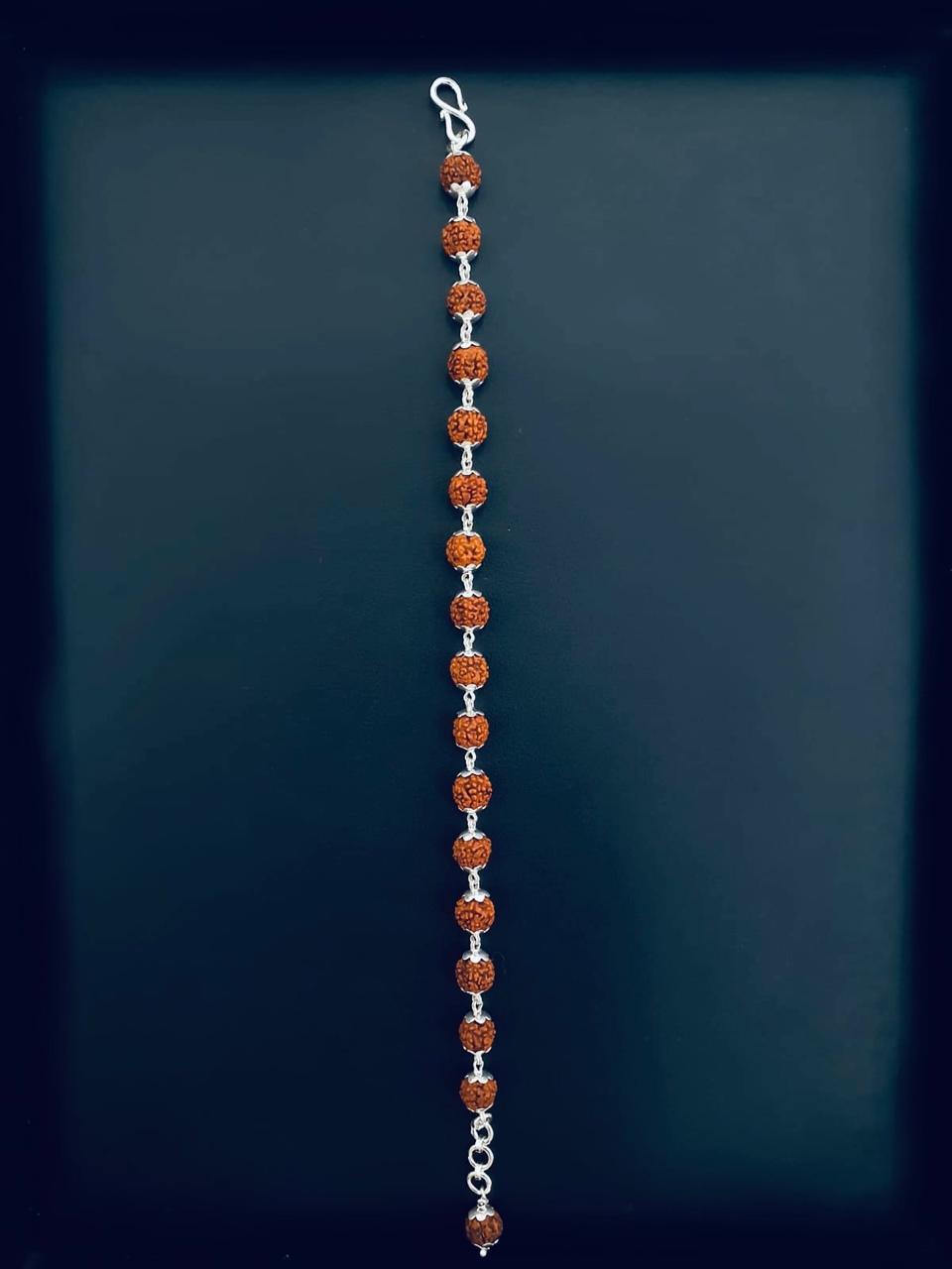 Bracelet of sixteen textured Rudraksha beads with silver-toned petal caps and an S-hook clasp on a dark background