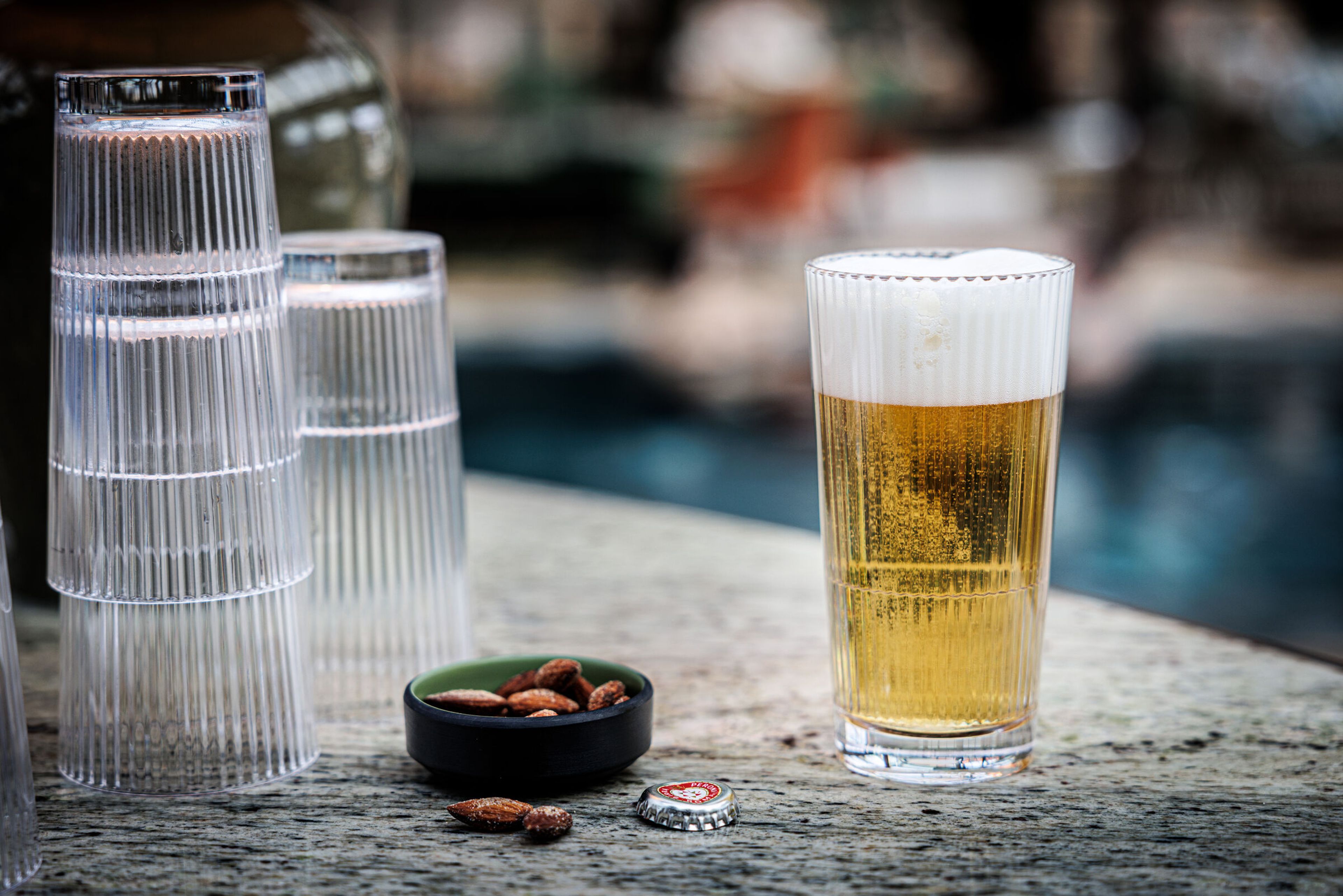 Öl i ett räfflat highballglas bredvid tomma glas.